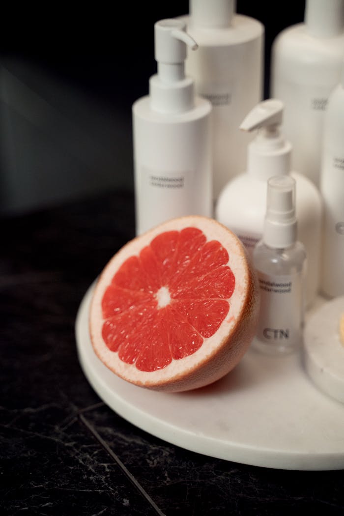 Collection of cosmetic products and a fresh grapefruit slice for a natural self-care routine.